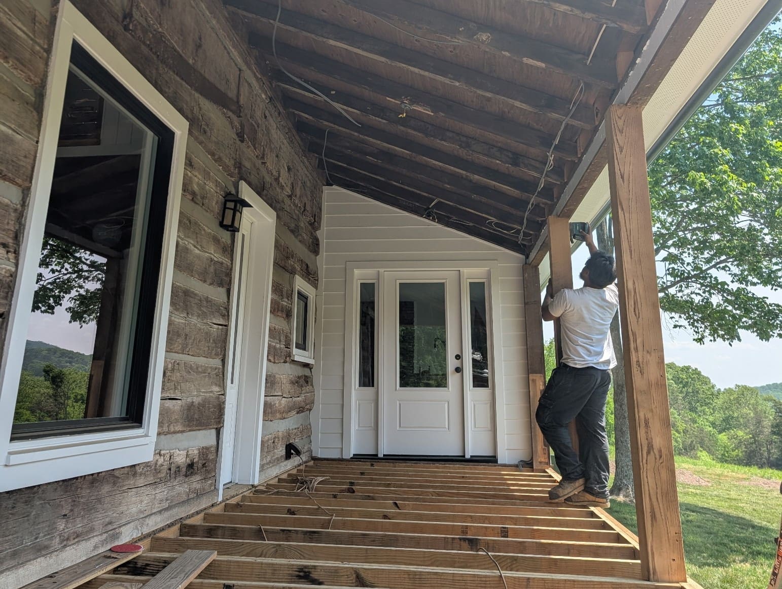 Porch renovation in progress on a historic log home with exposed roof framing and deck joists by a general contractor in Middle Tennessee.
