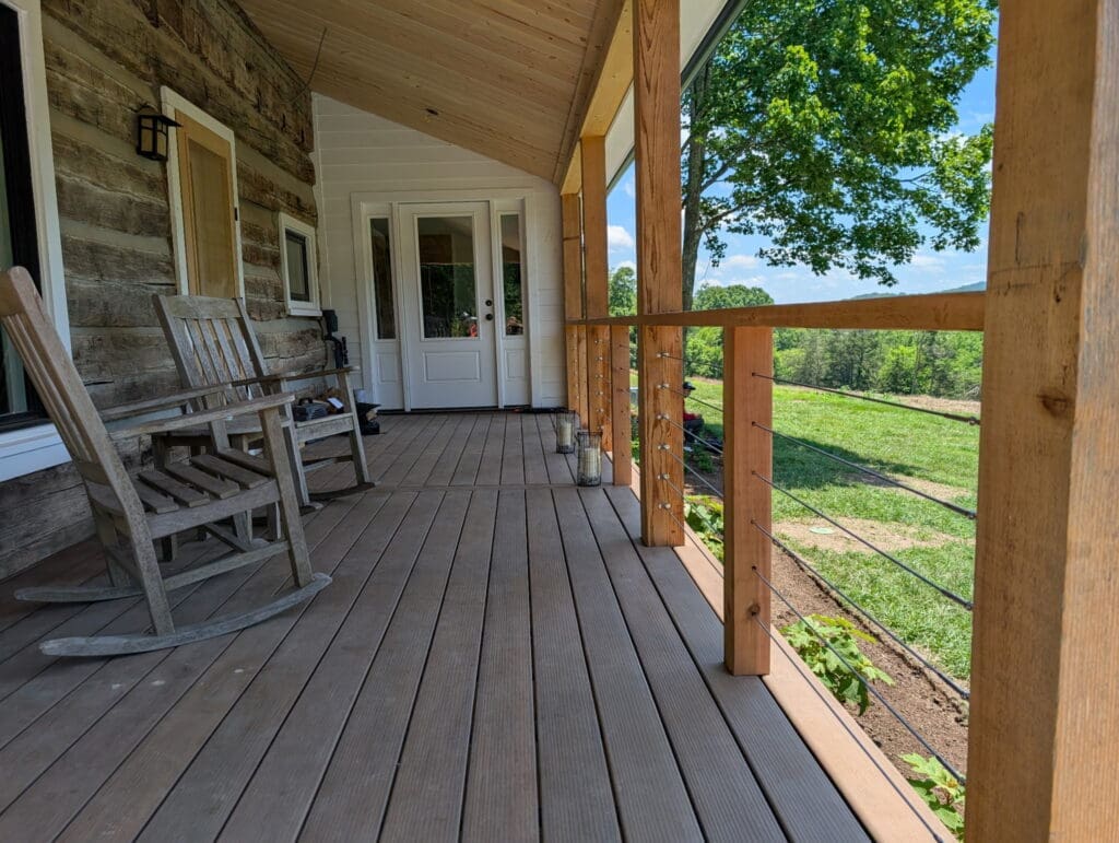 Finished rustic log home porch featuring cable railings and custom columns by an outdoor living contractor in Middle Tennessee.