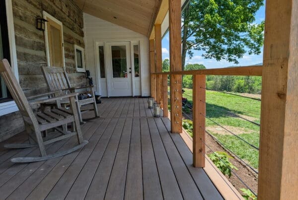 Finished rustic log home porch featuring cable railings and custom columns by an outdoor living contractor in Middle Tennessee.